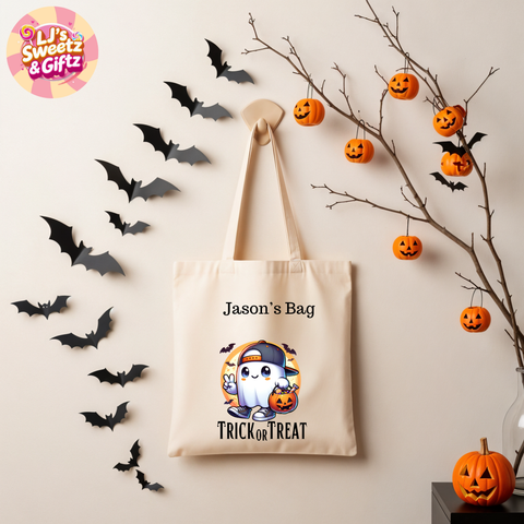 Beige tote bag with ghost design and text, surrounded by Halloween decorations on a light background.