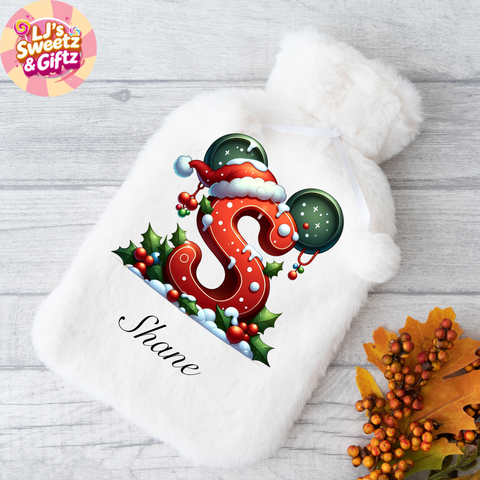 White fuzzy hat with a Christmas-themed letter 'S' design on a wooden surface.