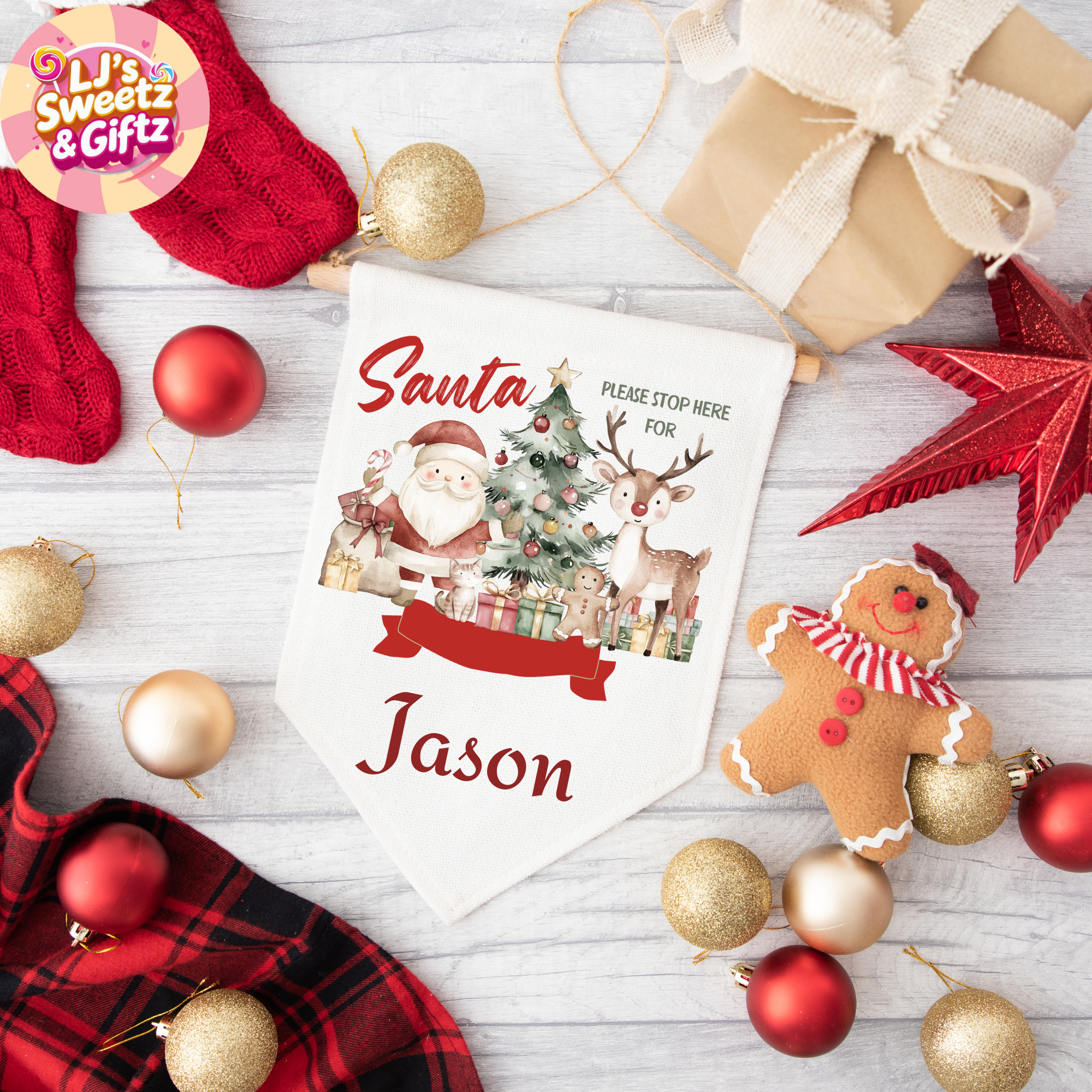 Personalized Christmas sign with Santa and reindeer design, surrounded by festive decorations on a wooden surface.