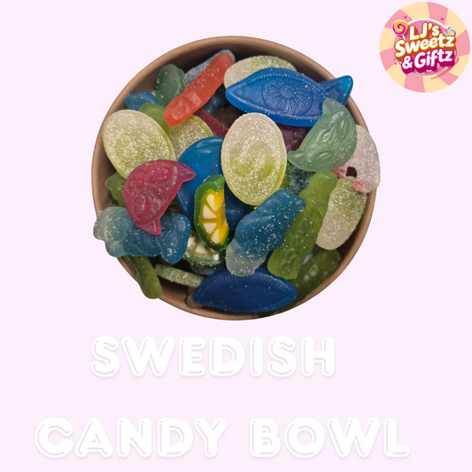 Bowl of colorful Swedish fish candy with 'LJ's Sweetz & Giftz' branding on a light pink background.